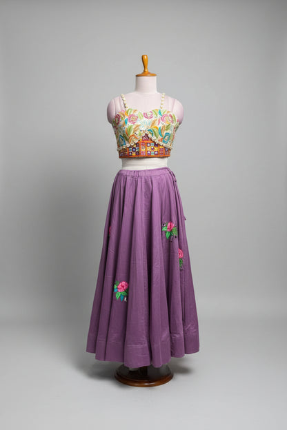 A purple traditional-style skirt with colorful floral embroidery displayed on a mannequin in a clothing store. The outfit includes a matching embroidered sleeveless top, shown against a background of other garments on racks.